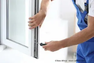 Salden u. Nicolaus Schlosserei GmbH - Ein Mann im blauen Overall repariert ein Fenster mit einem Schraubenzieher.