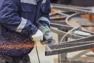 Salden u. Nicolaus Schlosserei GmbH - Ein Mann schleift mit einer Schleifmaschine ein Stück Metall.