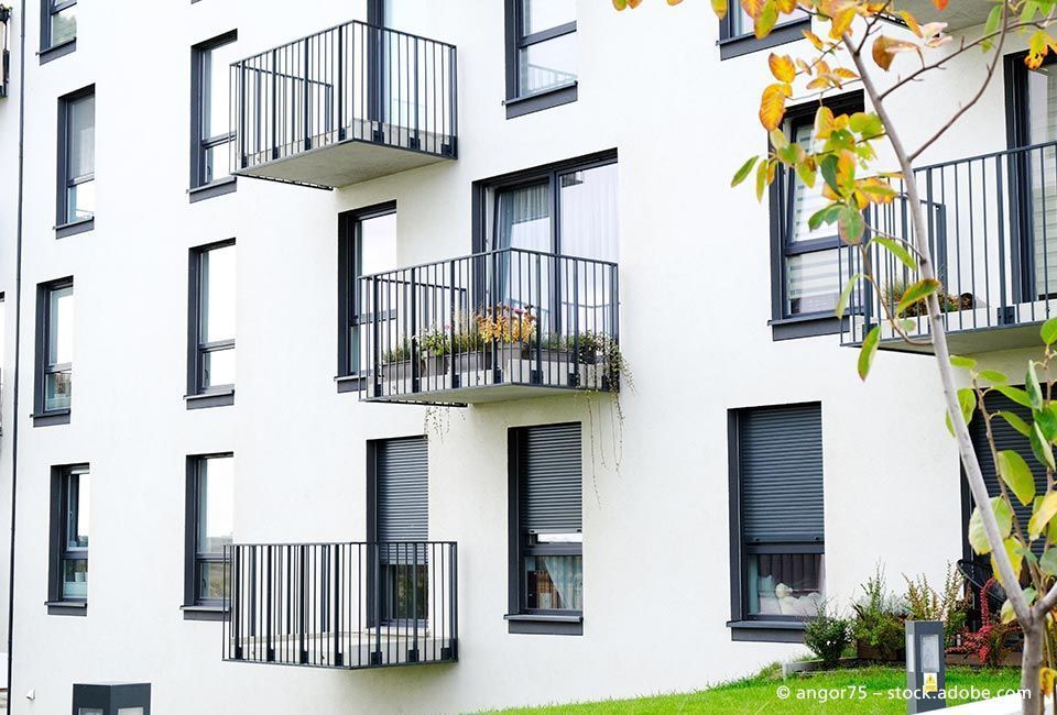 Salden u. Nicolaus Schlosserei GmbH - Ein weißes Wohnhaus mit Balkonen und einem Baum davor.