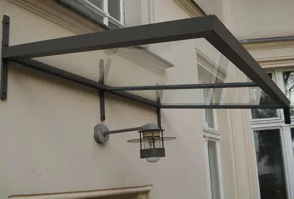 Salden u. Nicolaus Schlosserei GmbH - An der Seite eines Gebäudes befindet sich ein Baldachin mit einer daran befestigten Lampe.