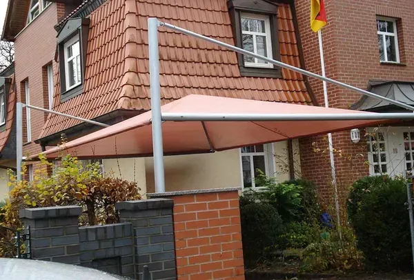 Salden u. Nicolaus Schlosserei GmbH - Ein Auto ist unter einem Sonnenschirm vor einem Backsteinhaus geparkt