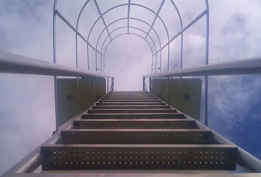 Salden u. Nicolaus Schlosserei GmbH - Eine Metalltreppe führt hinauf in einen wolkigen Himmel.