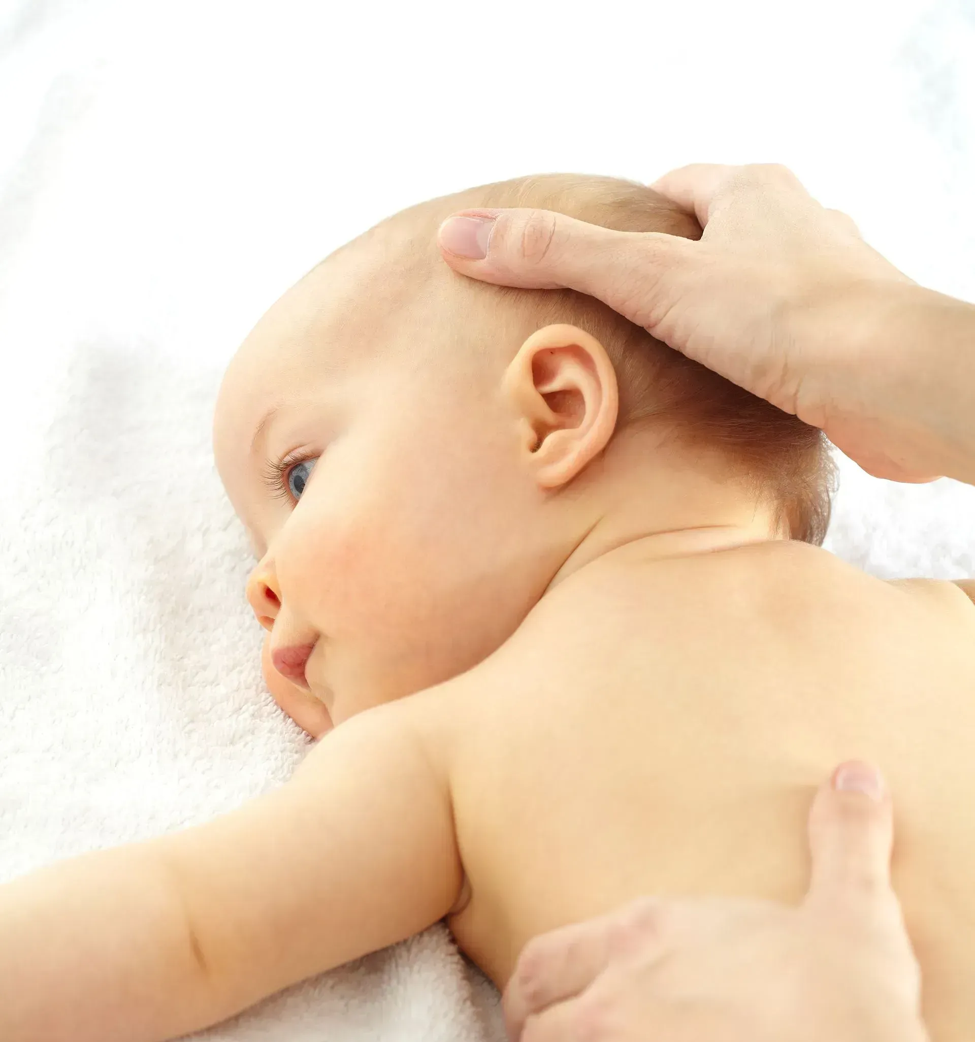 Un bébé est allongé sur une serviette blanche et reçoit un massage