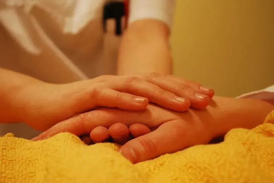 Une personne tient la main d'une autre personne sur une couverture jaune.