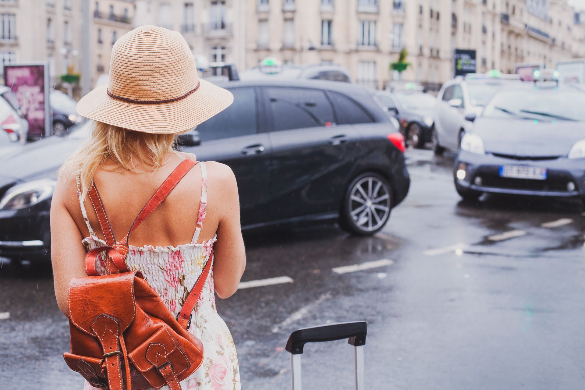 Femme avec sac à dos et valise en ville, essayant de héler un taxi