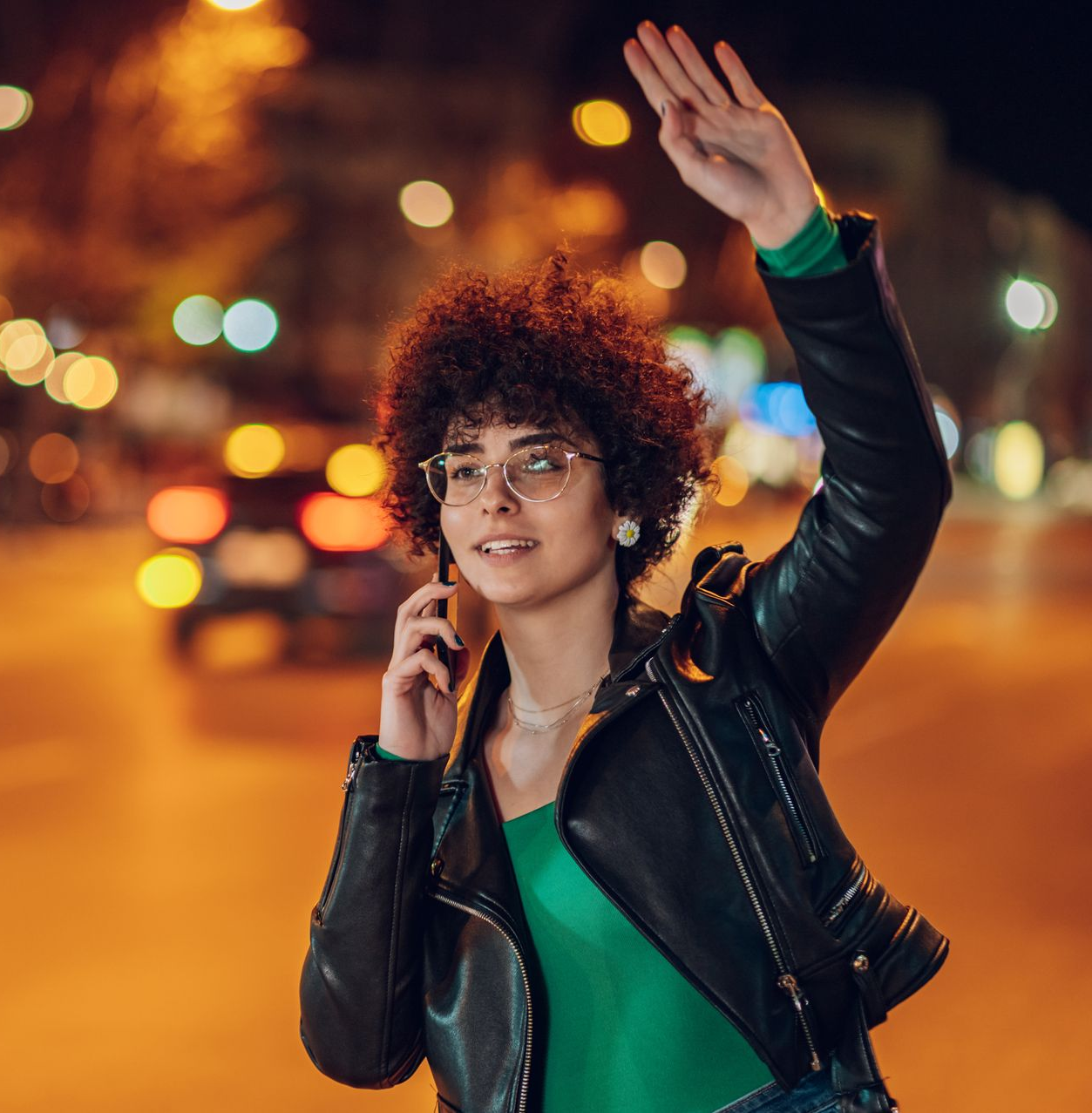 Une femme portant des lunettes hèle un taxi dans la rue la nuit