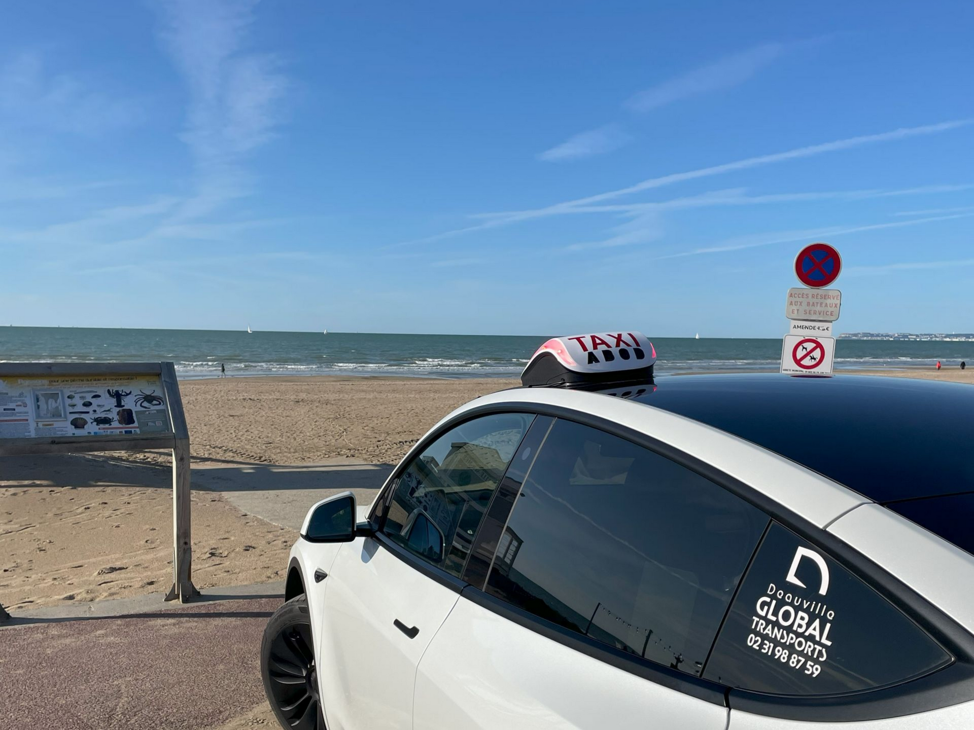 Taxi blanc garé sur une plage, l'océan en arrière-plan