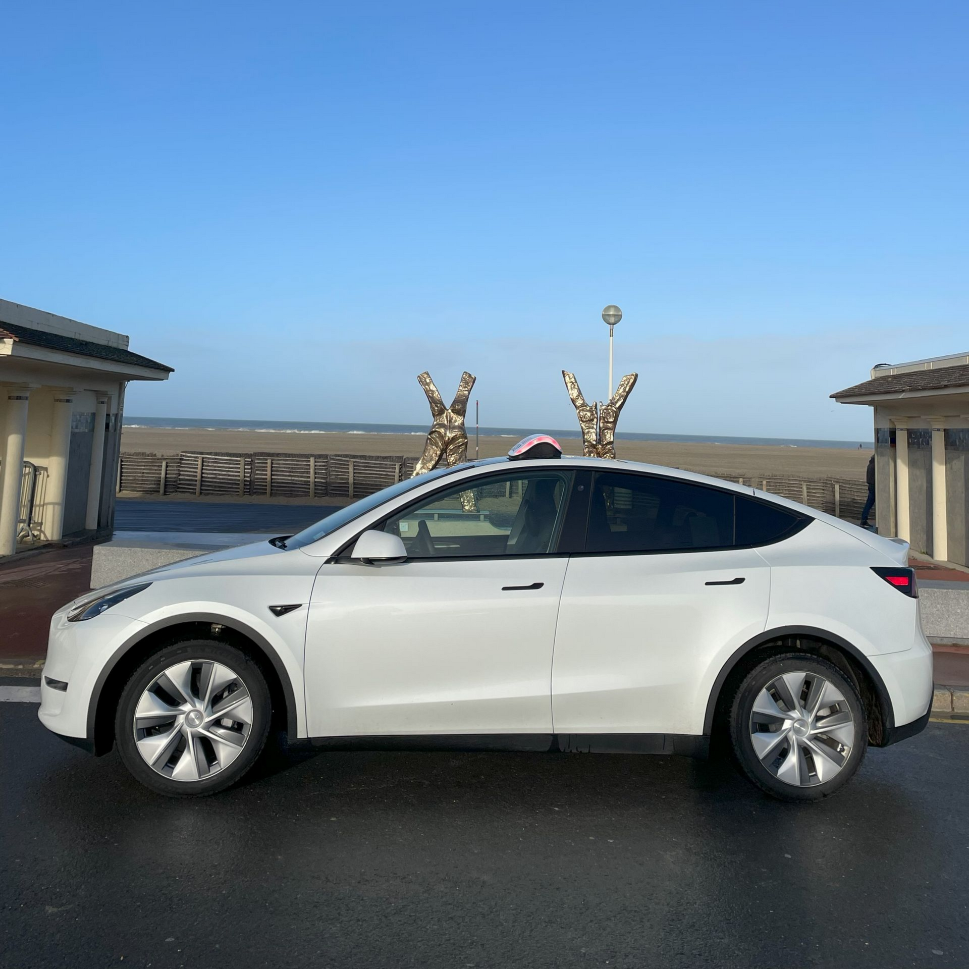 Tesla Model Y blanche garée au bord de mer par une journée ensoleillée