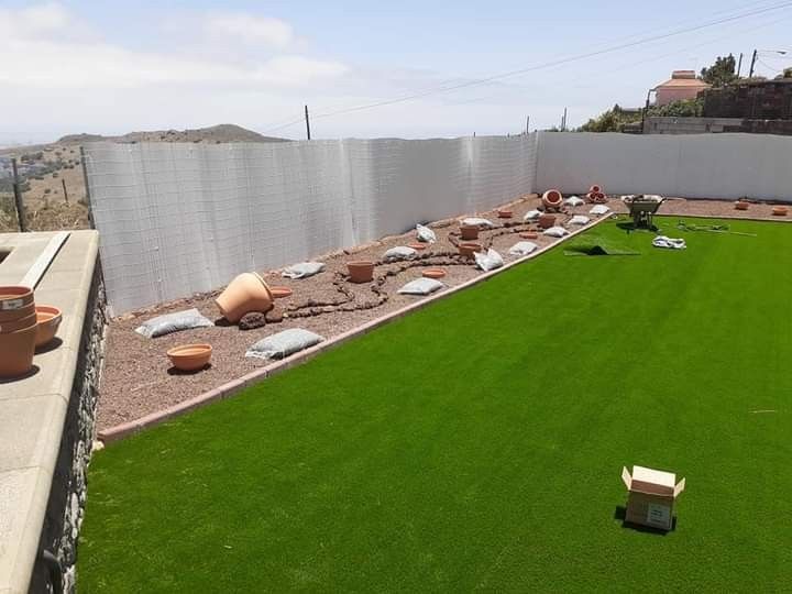 Terraza en la azotea con césped artificial de color verde brillante y plantas en macetas.