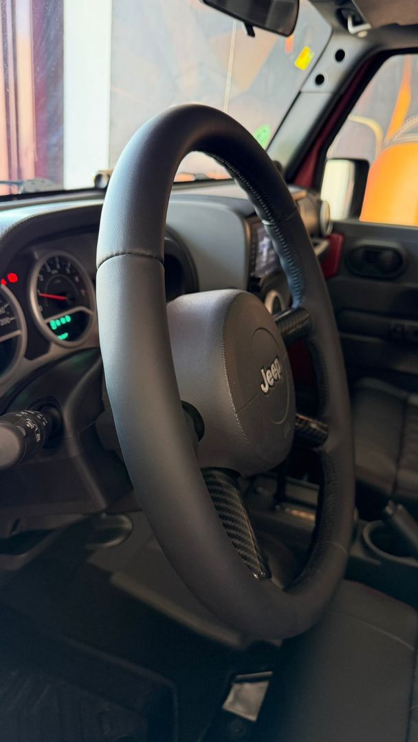 Interior de un coche con volante y salpicadero negros, visto desde el asiento del conductor.