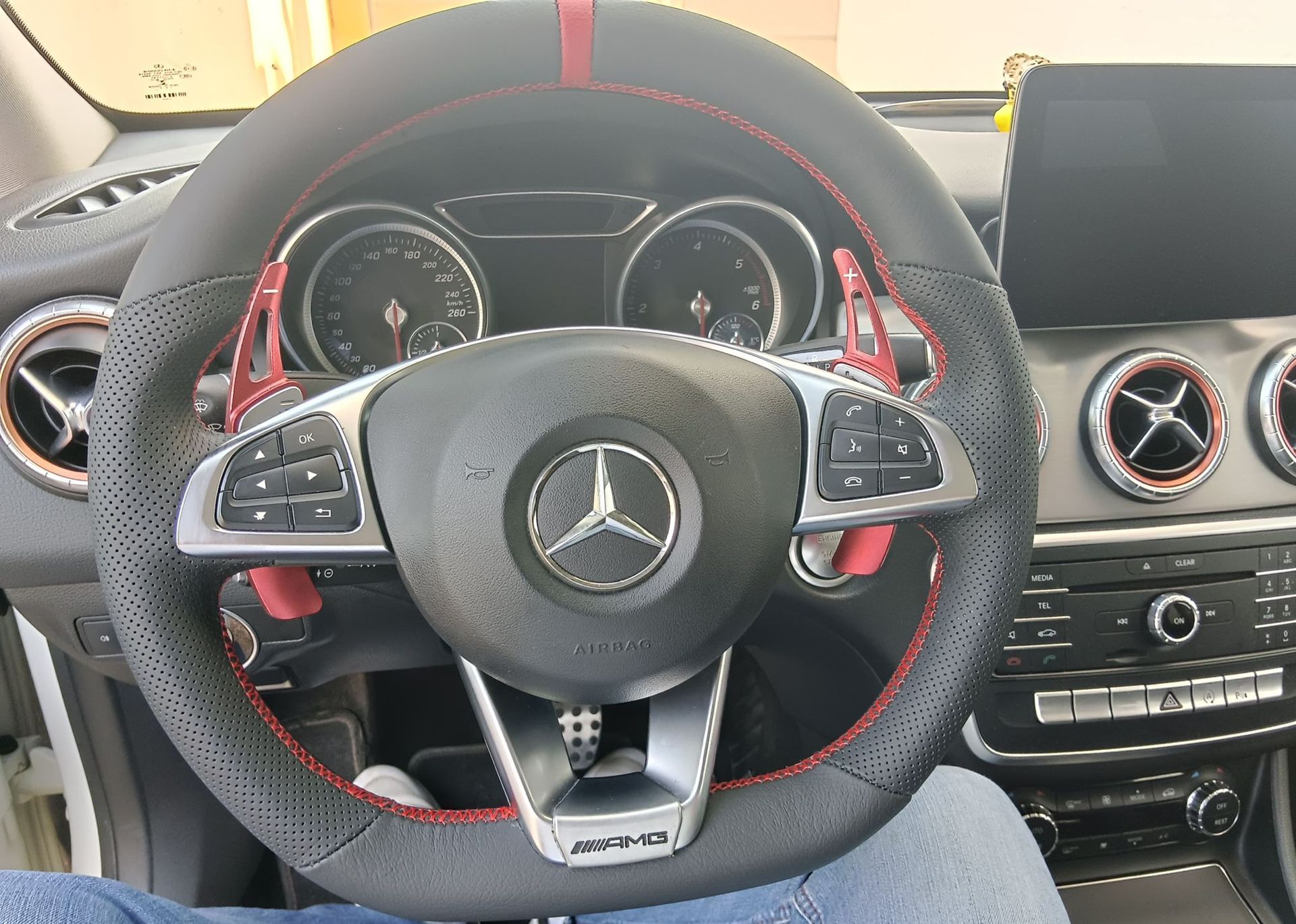 Volante Mercedes-Benz con costuras rojas y salpicadero vistos desde el asiento del conductor.