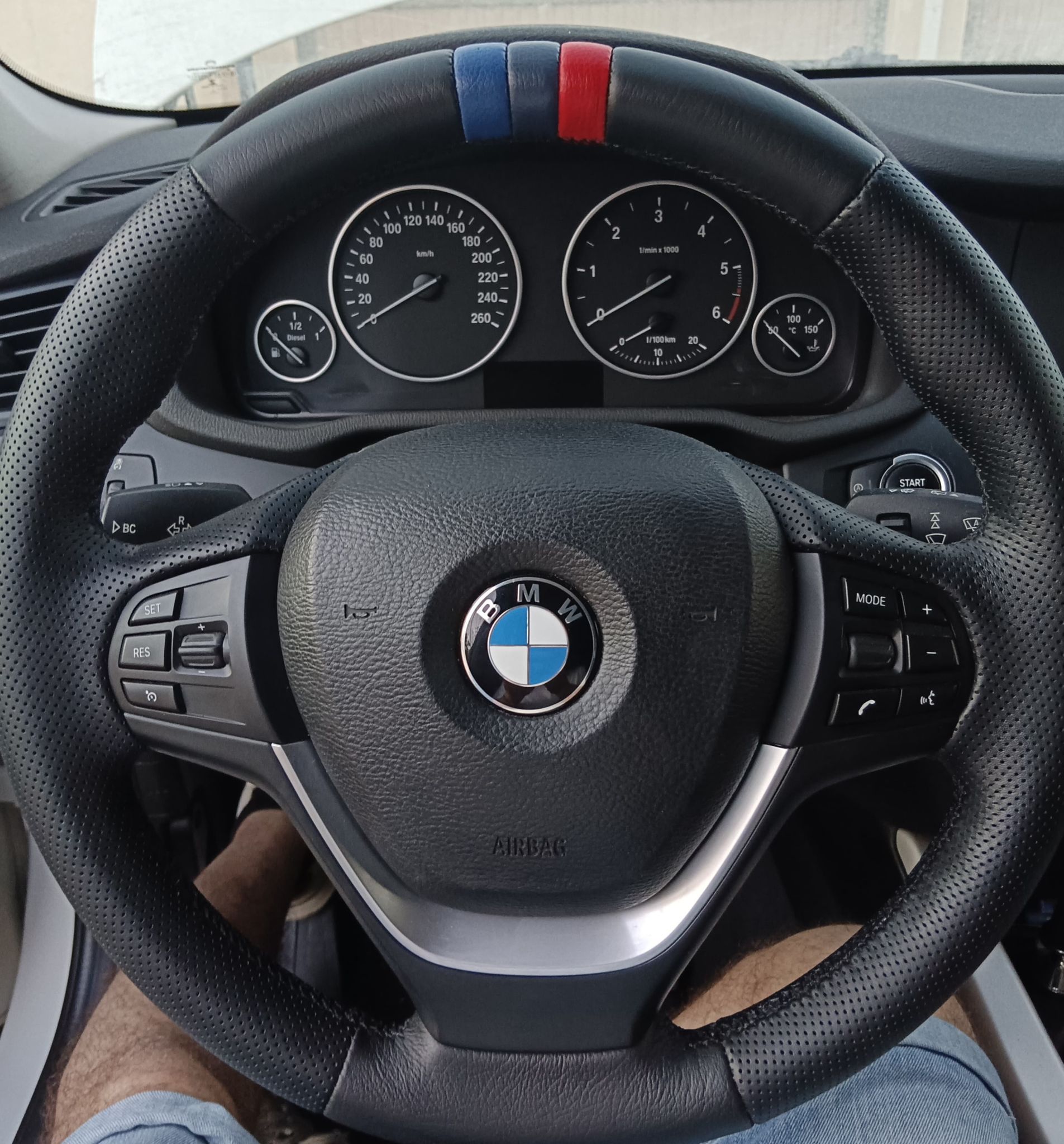 Interior del volante y del salpicadero de BMW, con marcadores rojos y azules en la parte superior del volante.