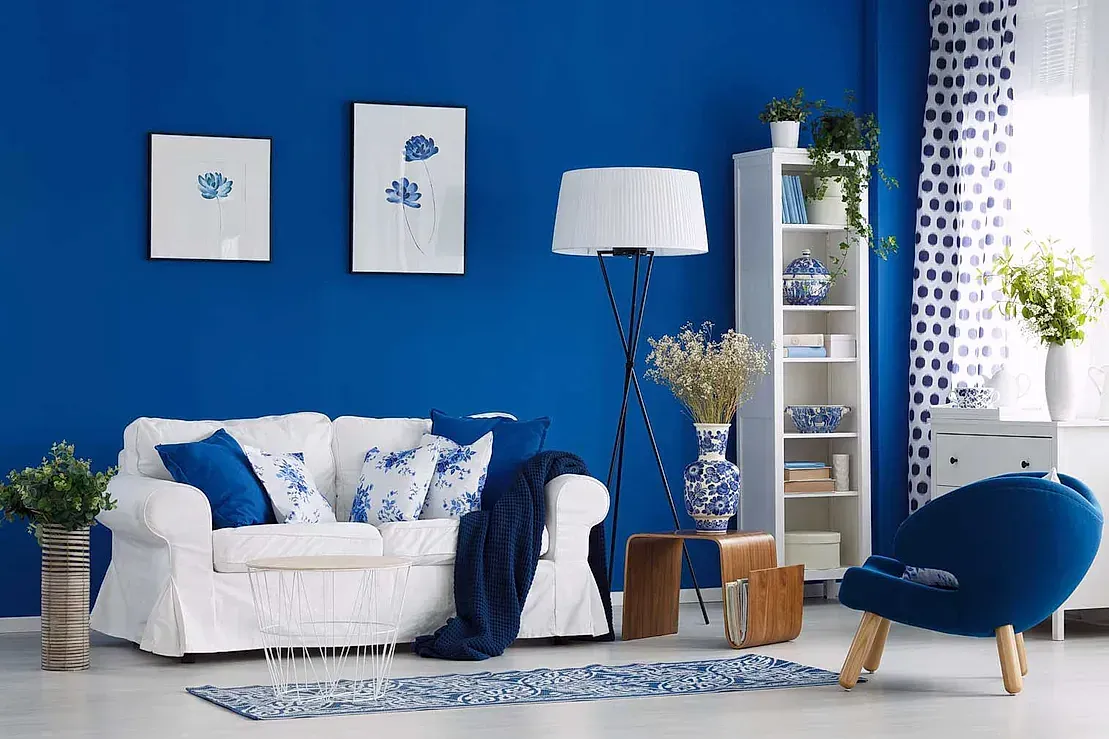 Una sala de estar con paredes azules y muebles blancos.