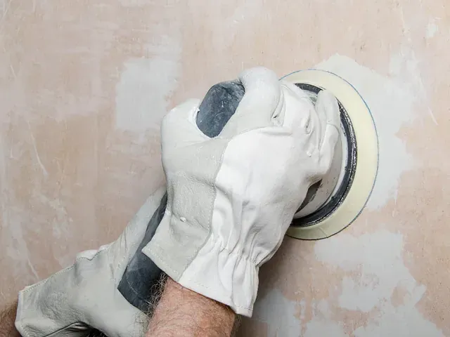 Una persona está lijando una pared con una lijadora.