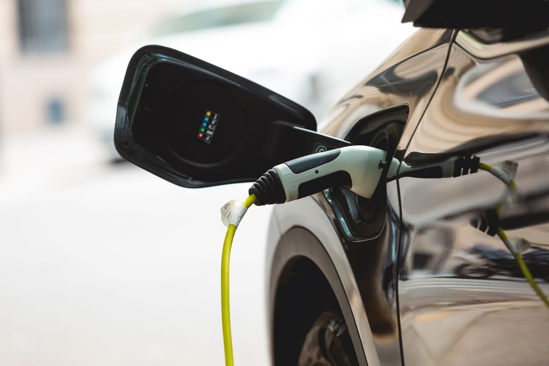 Voiture électrique en charge à une borne, avec un câble jaune branché sur le port avant.