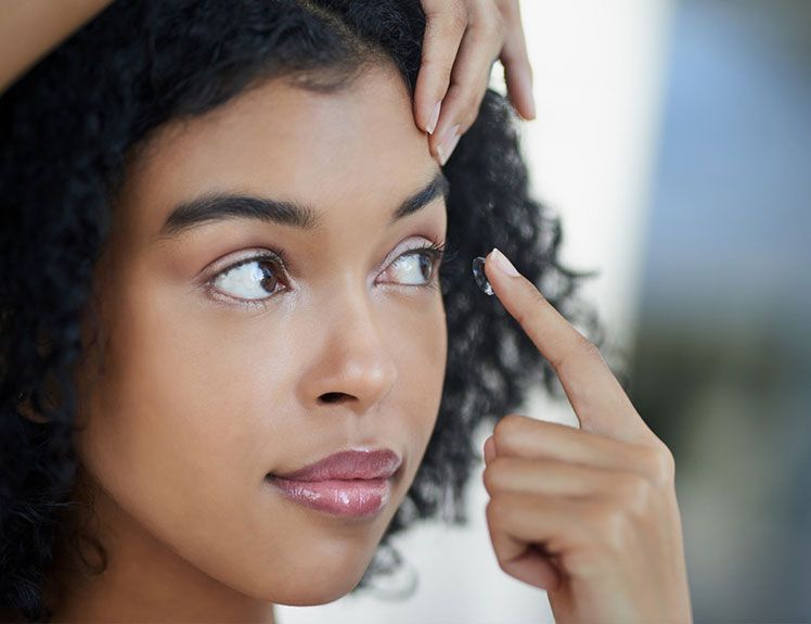 Une femme se met une lentille dans l'oeil
