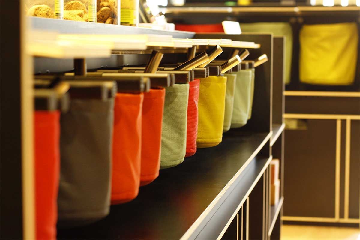 Una fila de bolsas de colores están alineadas en un estante.