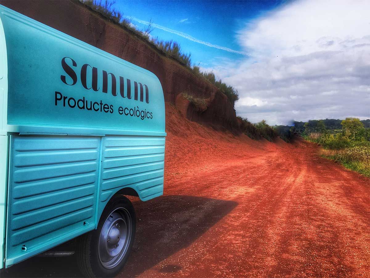 Una camioneta azul está estacionada al costado de un camino de tierra.