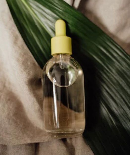 Una botella con un gotero encima de una hoja verde.