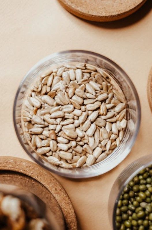 Un recipiente de vidrio lleno de semillas de girasol sobre una mesa.