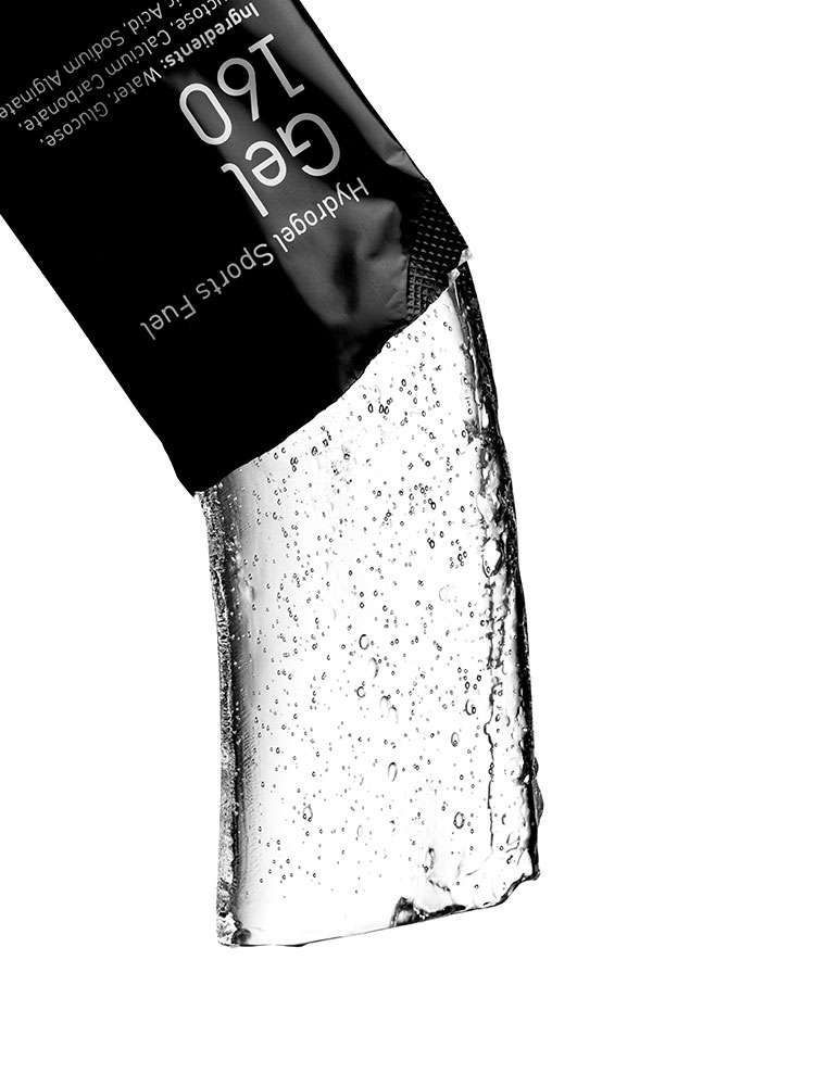 Una mancuerna, pesas, guantes y una botella de proteína en polvo sobre un fondo blanco.
