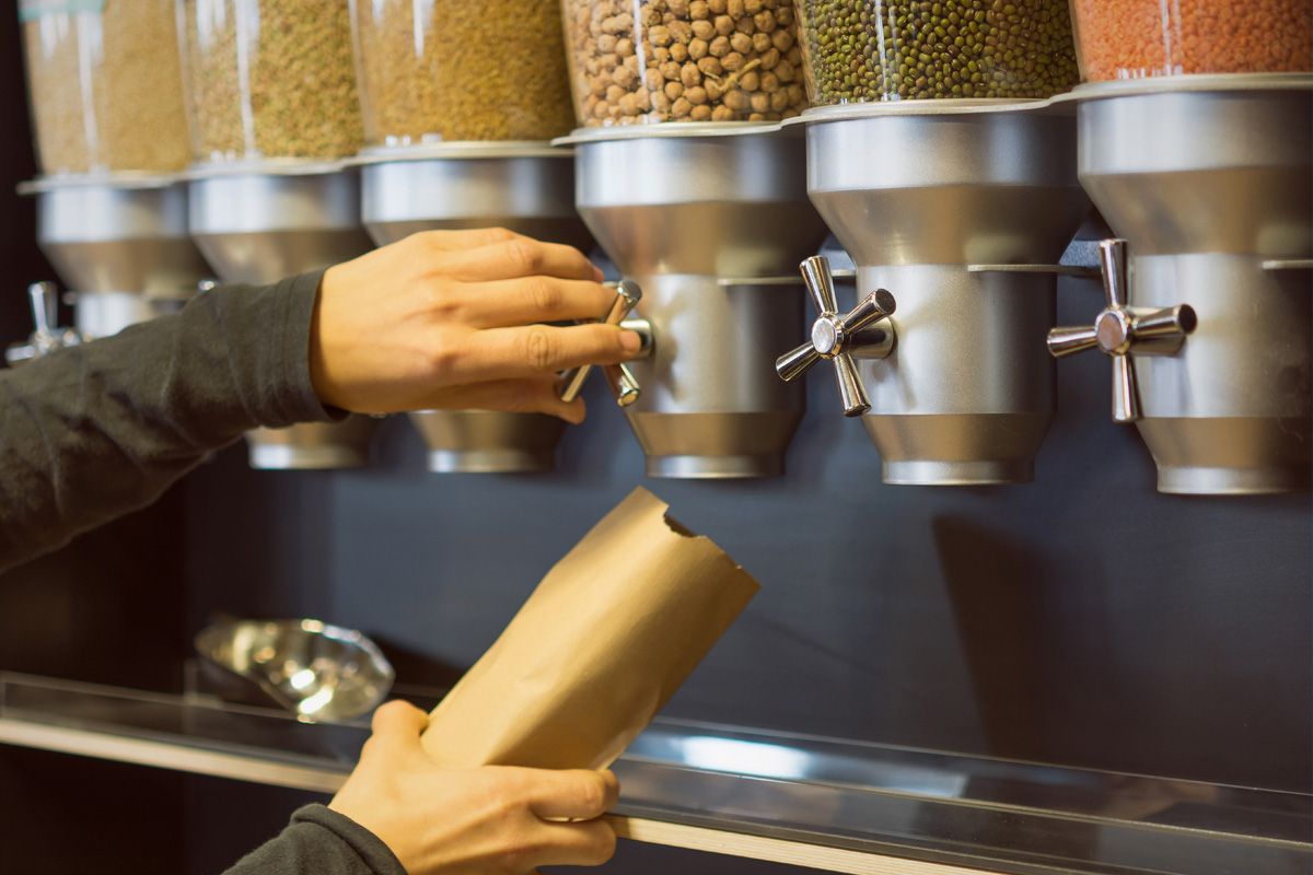 Una persona está vertiendo semillas en una bolsa en una tienda de comestibles.