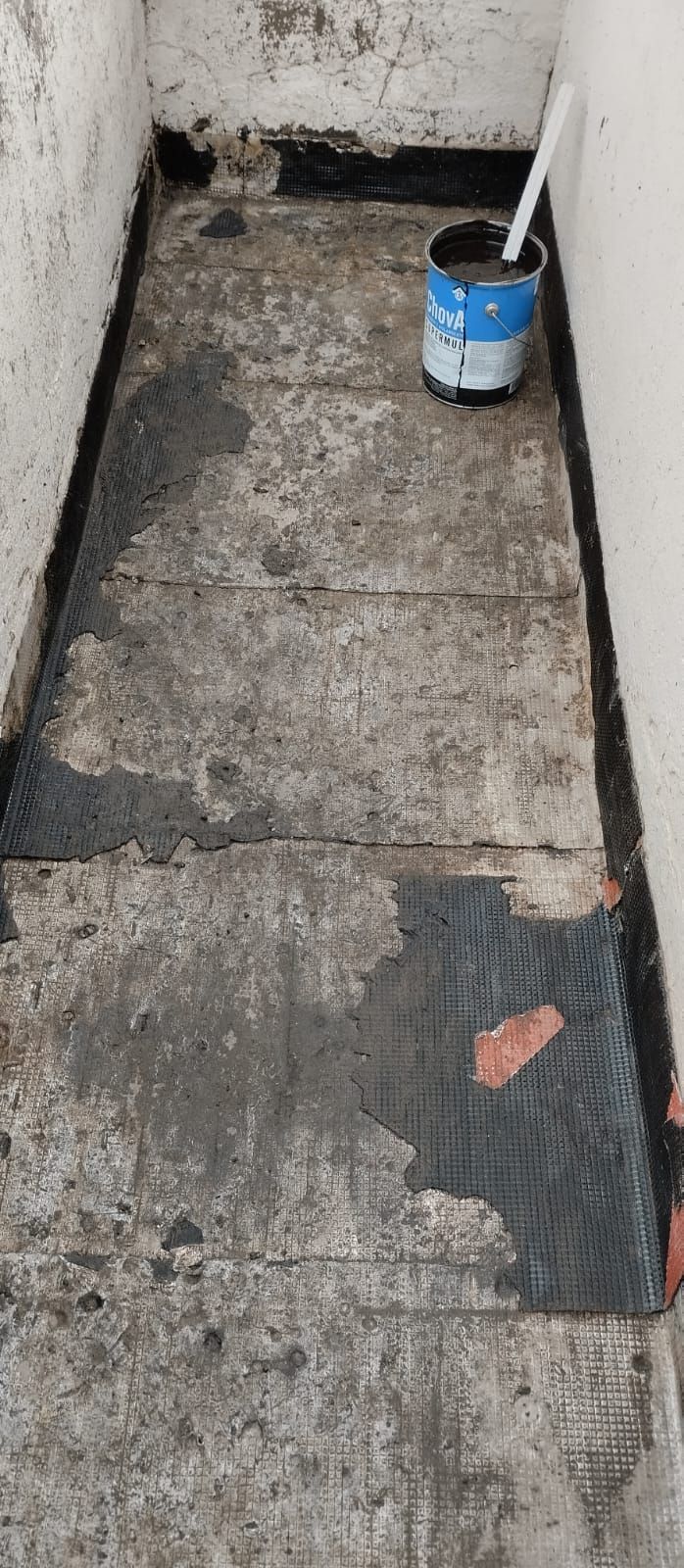 Un baño sucio con un balde de pintura y un cepillo de baño en el suelo.