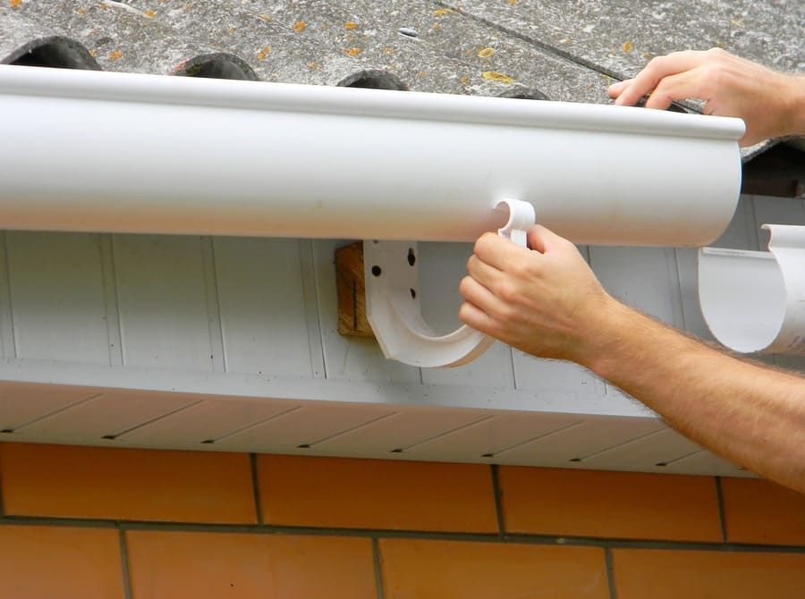 Una persona está instalando una canaleta blanca en un tejado.