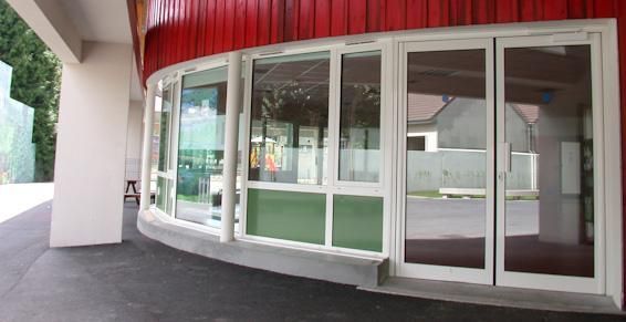 Façade de bâtiment incurvée avec fenêtres en verre et bardage rouge.