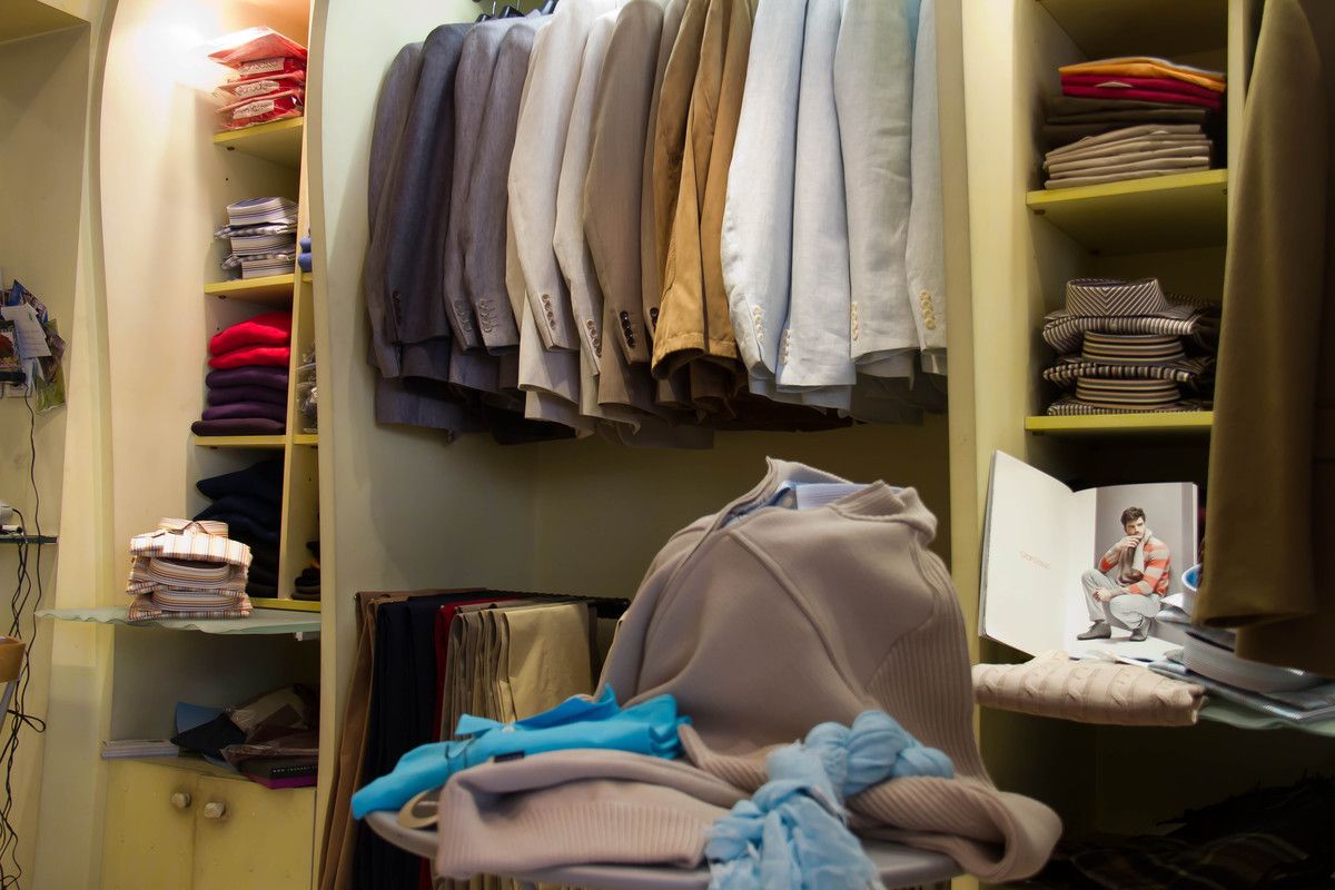 Intérieur d'un magasin de vêtements avec des vestes suspendues à une tringle et des pulls empilés sur des étagères.