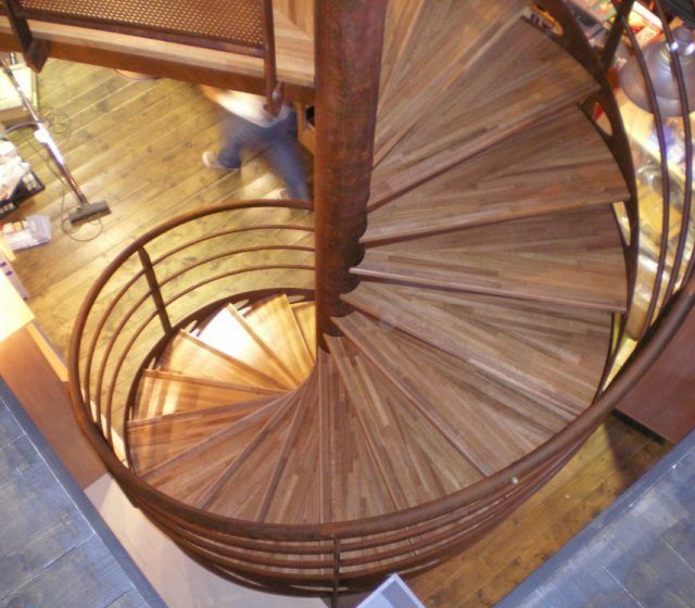 Escalier en colimaçon avec marches en bois et rampe en métal.