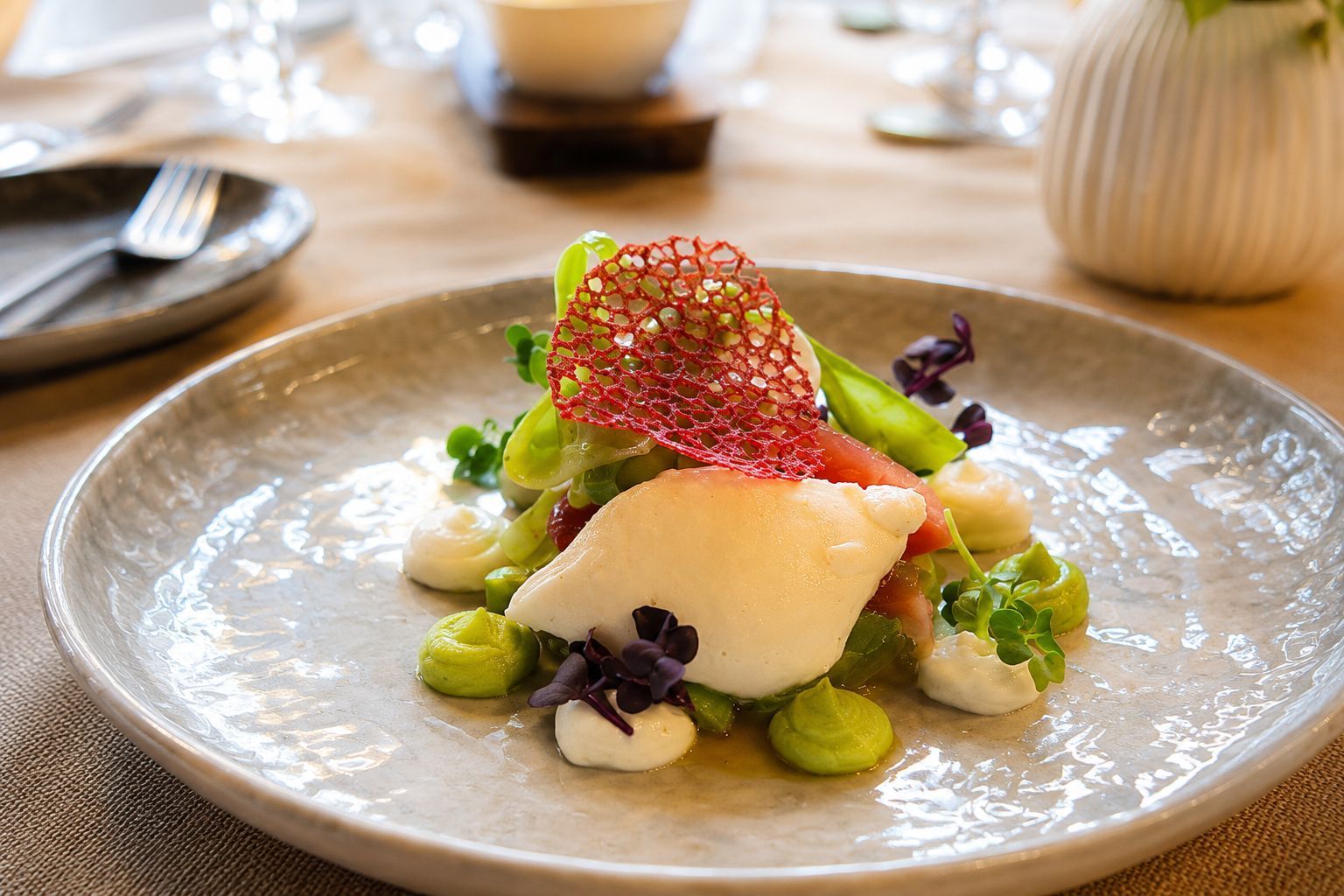 Ein Gourmet-Gericht mit Gemüse, Käse und einer knackigen Garnitur auf einem weißen Tisch.