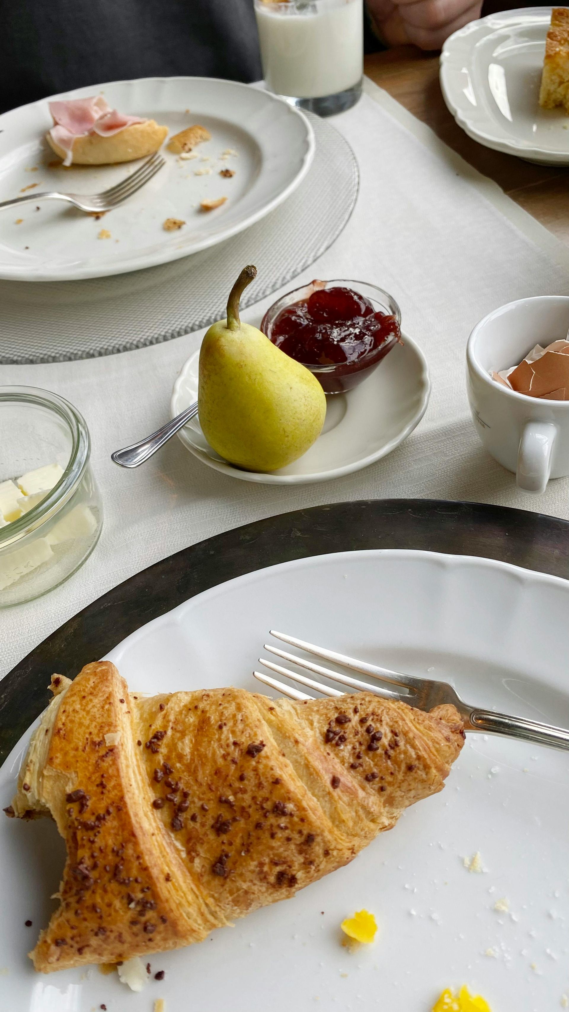 Tisch mit Crêpes, Obst, Marmelade und Getränken auf weißen Tellern bei einem Brunch