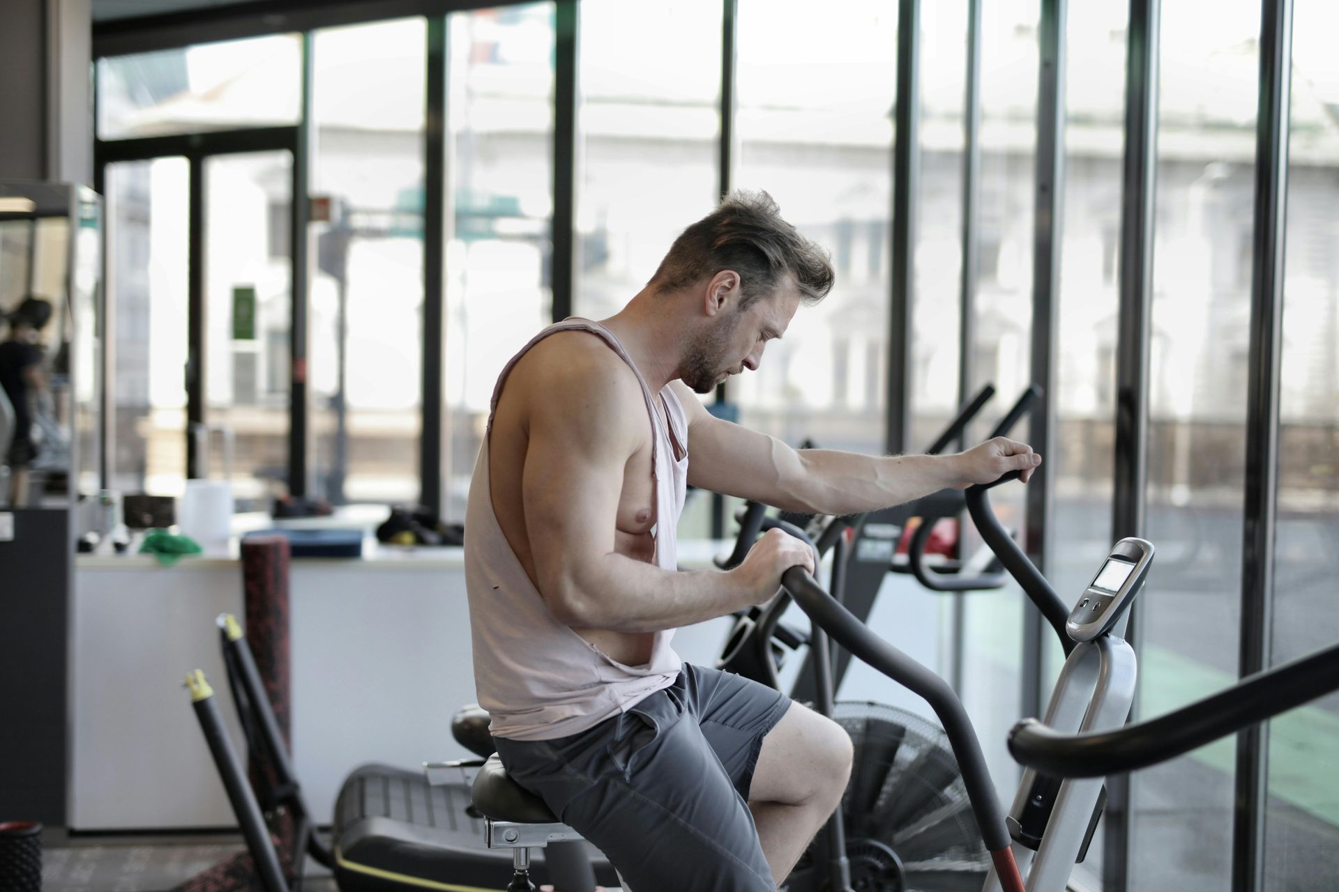 Ein Mann trainiert auf einem Ellipsentrainer in einem Fitnessstudio und konzentriert sich auf ein Tablet am Lenker.