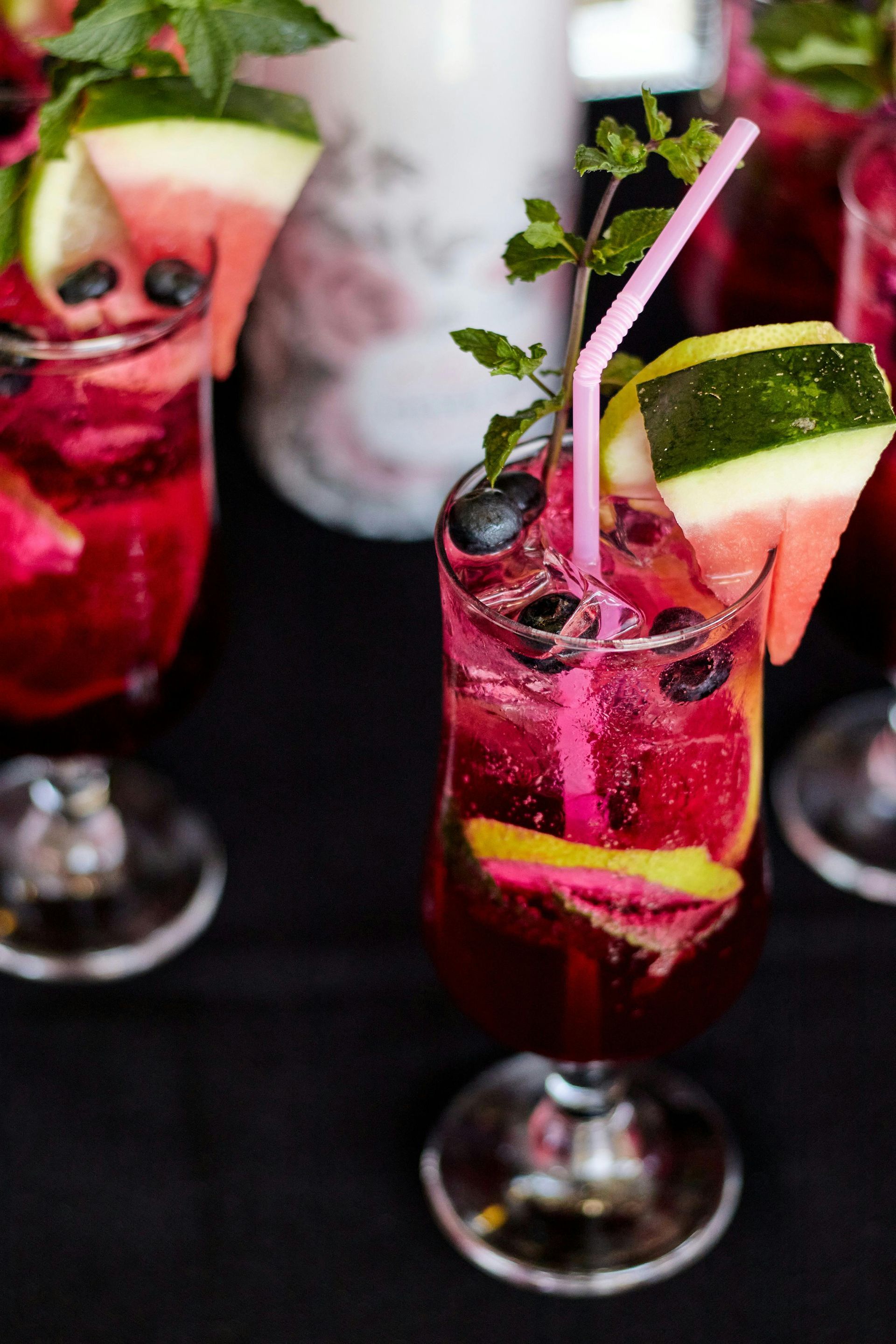 Rosa Cocktails mit Wassermelonen- und Gurkengarnitur auf einem dunklen Tisch