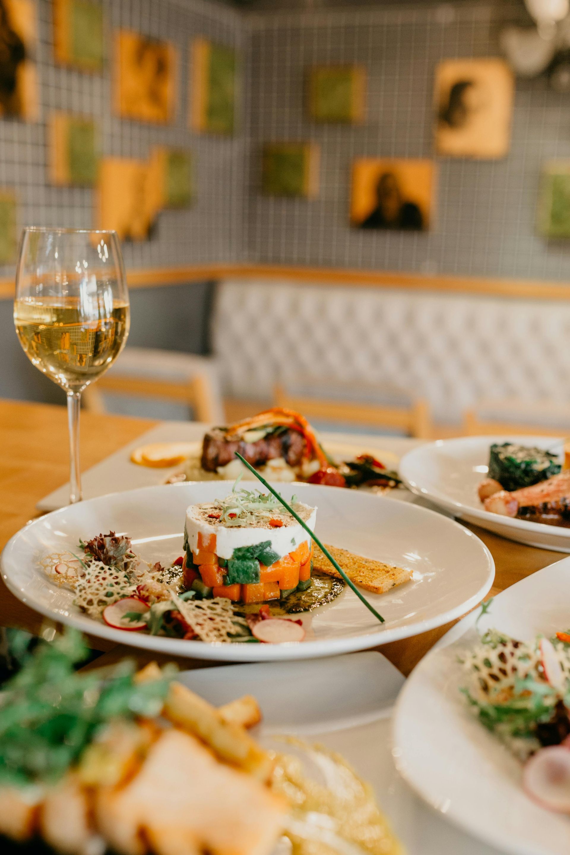 Restauranttisch mit angerichteten Gourmetgerichten und einem Glas Weißwein