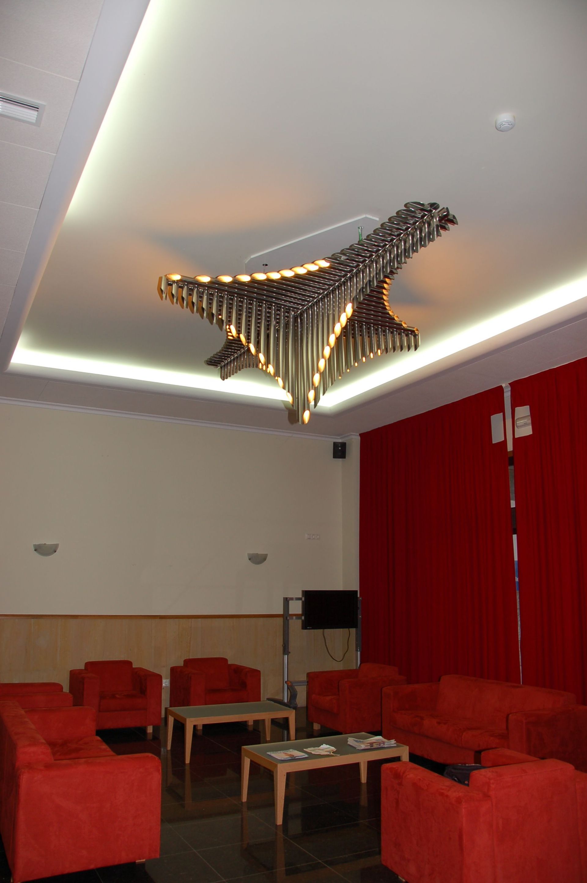 Una sala de estar con sillas rojas y una lámpara de araña en forma de avión.