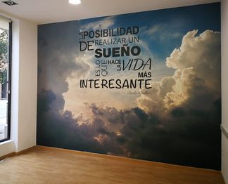 Una pared con una imagen de nubes y una cita en ella.