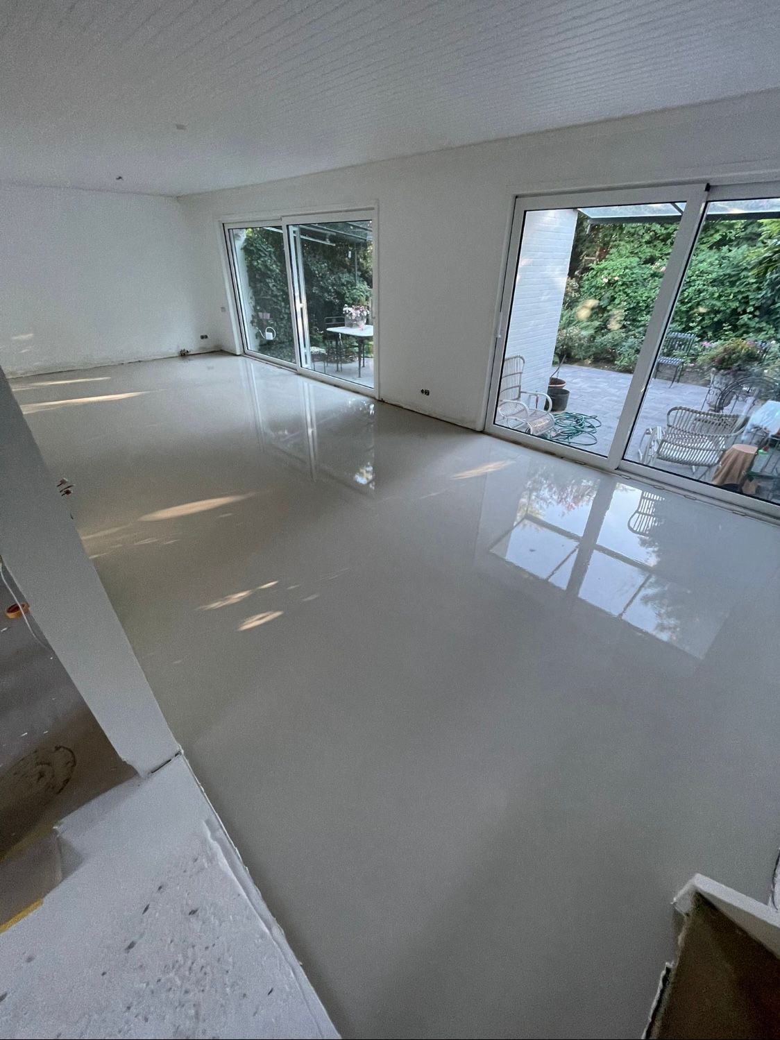 ein großer leerer Raum mit vielen Fenstern und einem weißen Boden.