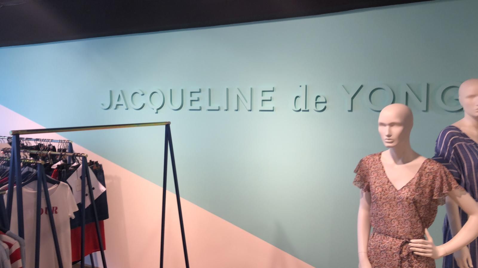 Schaufensterpuppen vor einer Wand, auf der Jacqueline de Yong steht