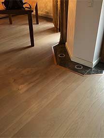 ein Holzboden in einem Wohnzimmer mit Tisch und Stühlen.