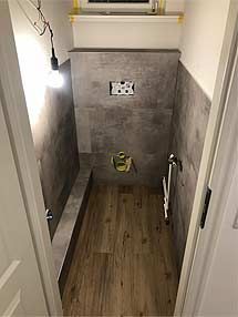 ein kleines Badezimmer mit Holzboden und einer Toilette.