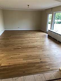 ein leeres Wohnzimmer mit Hartholzböden und einem großen Fenster.