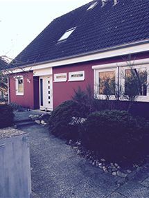 ein rotes Haus mit schwarzem Dach und vielen Fenstern.