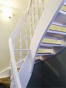 Eine weiße Holztreppe mit weißem Geländer in einem Raum.