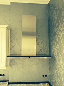 eine Küche mit einer Dunstabzugshaube aus Edelstahl an der Wand.