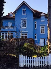 ein blaues Haus mit einem weißen Lattenzaun davor.