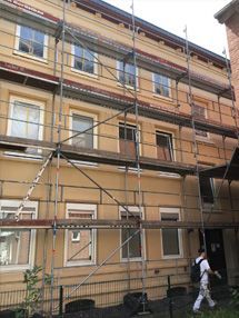 Ein Mann geht vor einem Gebäude, das von einem Baugerüst umgeben ist.