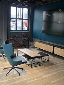 ein Wohnzimmer mit Stühlen, einem Couchtisch, einem Fahrrad und einem Flachbildfernseher.