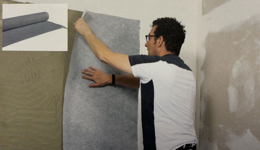 Ein Mann hält ein Stück Stoff an einer Wand.